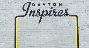 Dayton Inspires black lettering wall mural on a gray brick background
