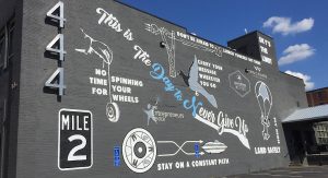 This is the day to never give up mural on dark gray wall. Several images of flight and propulsion 