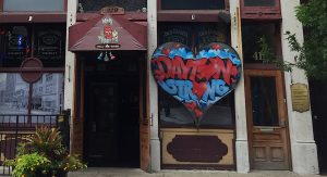 Dayton Strong graffiti lettering inside a metal heart near a store front